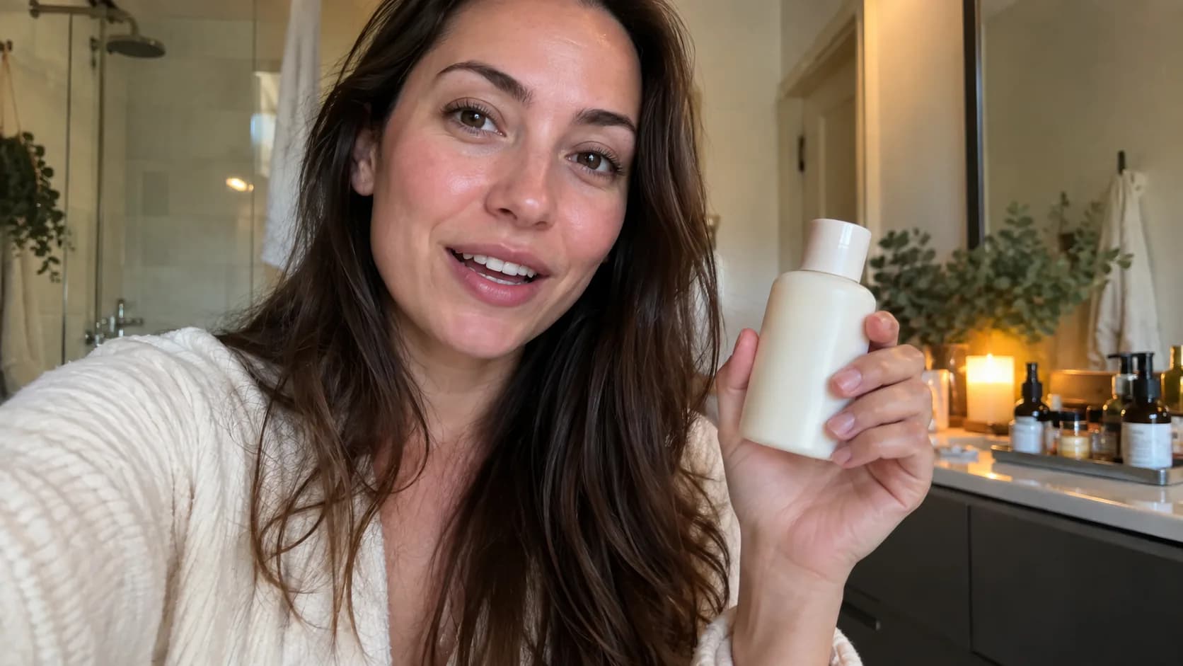 Beauty creator holding an unbranded lotion bottle in a natural bathroom setting